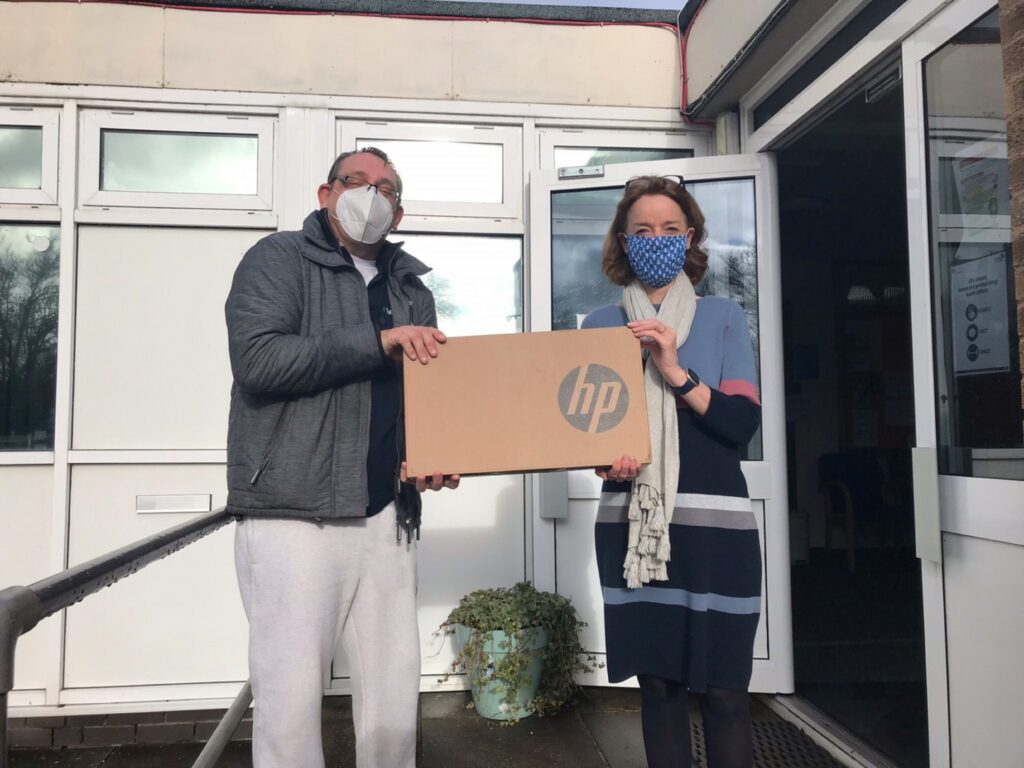 Paul Shackleford, Soha's Digital Inclusion and Employment Support Advisor, on the steps of Abbey Wood School with the headteacher. He is handing over a laptop.